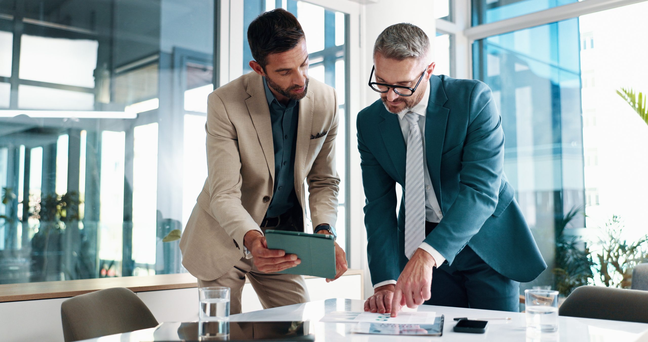 Two men in suits reviewing a document.